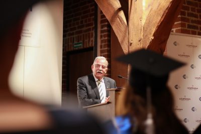 Bürgermeister Eduard Kolle aus Lüneburg gratuliert Absolvent*innen des MBAs am Rednerpult im Glockenhaus