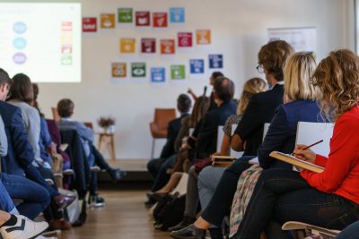 Teilnehmer*innen der Fachkonferenz hören Vortrag zu den SDGs