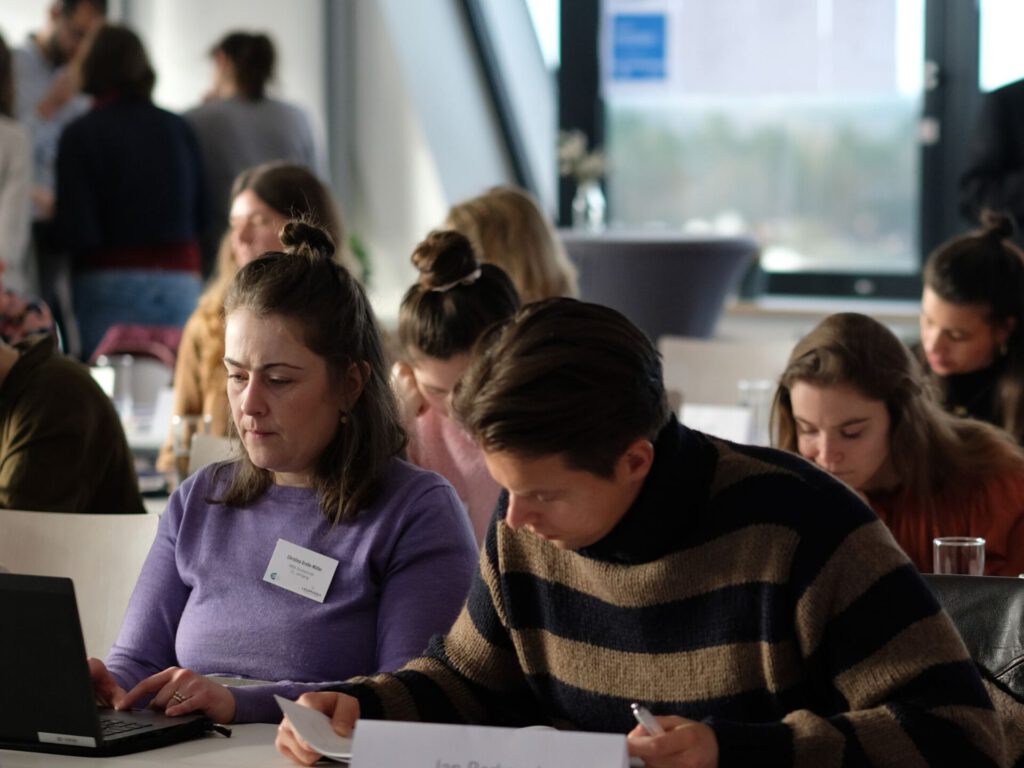 Die Studierenden sitzen in mehreren Reihen hinter- und nebeneinander und arbeiten konzentriert.